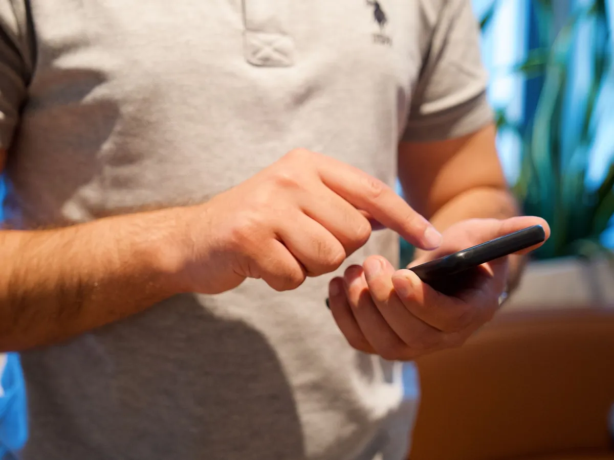 Man past instellingen aan op zijn smartphone in een lichte ruimte