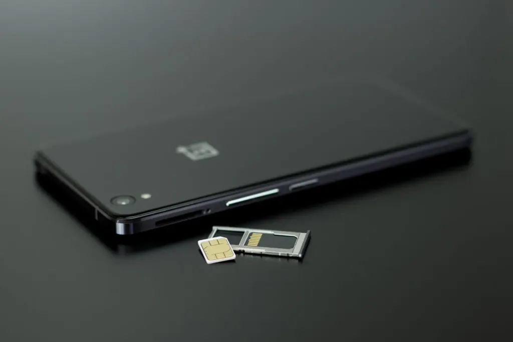 Smartphone met geopende simlade, simkaart en geheugenkaartje op een donkere ondergrond