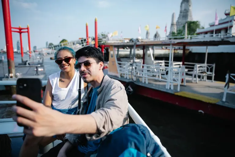 Stel maakt een selfie op een boot op de rivier in Bangkok met een tempel op de achtergrond
