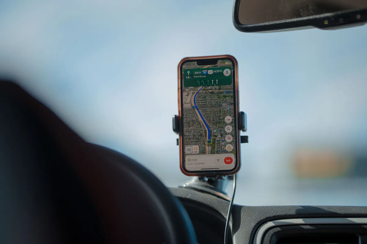 Smartphone met navigatieapp in een houder op het dashboard tijdens een autorit